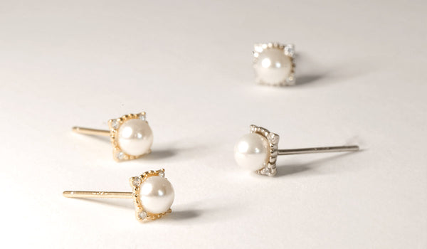 Exquisite gold and silver stud earrings adorned with lustrous pearl centers and delicately accented by four shimmering diamonds.
