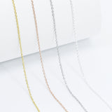 close up shot of four thin, minimalistic cable chain style layering necklaces in silver, frosted silver, gold and rose gold 