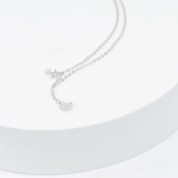 cute sterling silver necklace featuring a small moon pendant made up of cubic zircona and a small star charm with a small cubic zircona stone attached 