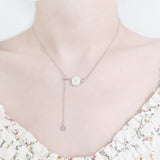 close up neck and collarbone shot of female wearing pretty floral top and delicate sterling silver necklace featuring a flower pedant and two cubic zircona stones