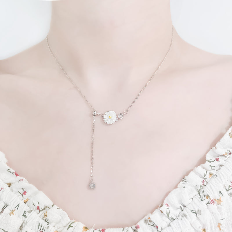 close up neck and collarbone shot of female wearing pretty floral top and delicate sterling silver necklace featuring a flower pedant and two cubic zircona stones