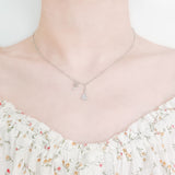 close up of girl's neck and collarbone wearing a pretty floral top and a cute sterling silver necklace featuring a small moon pendant made up of cubic zircona and a small star charm with a small cubic zircona stone attached